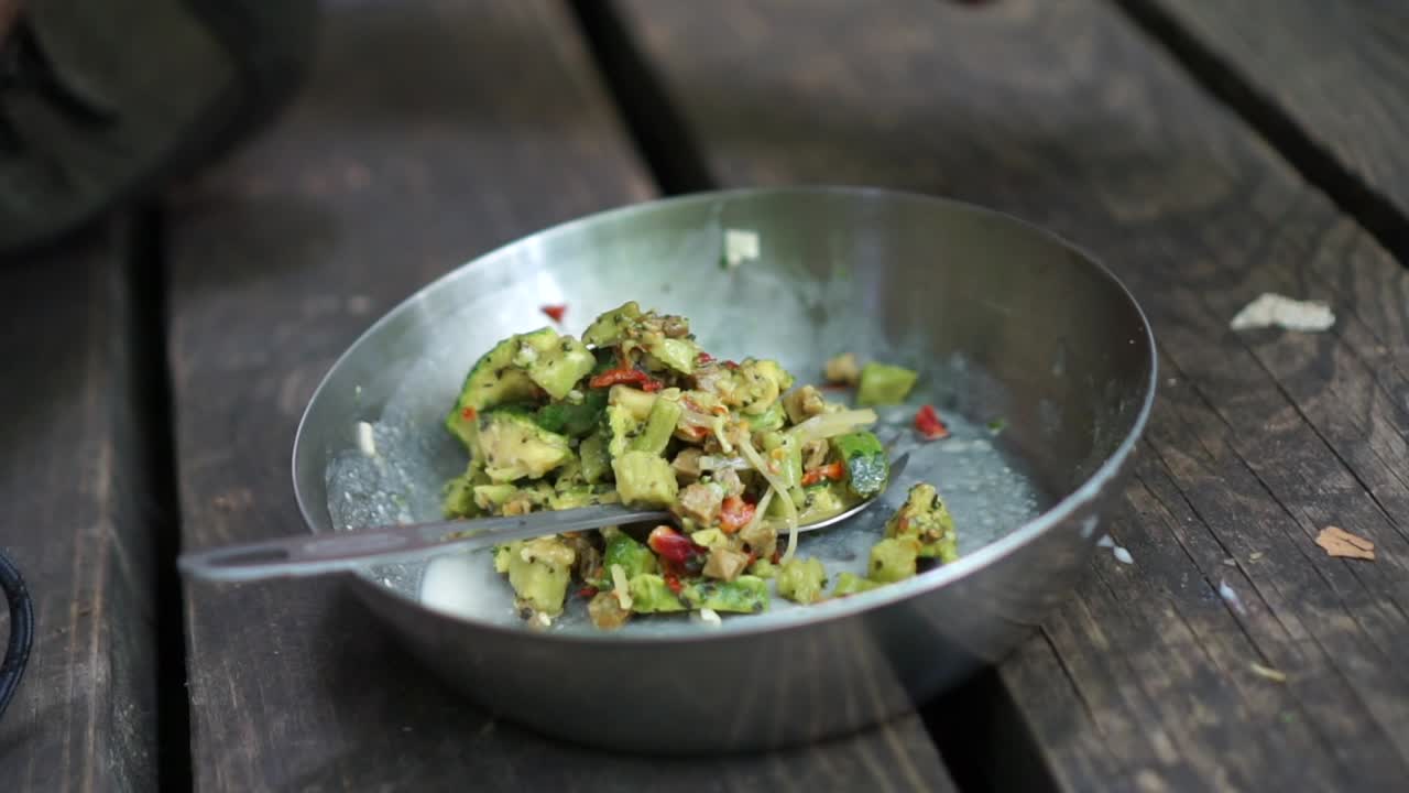 패킷에서 캠핑 접시에 캠핑 음식을 붓는 남자