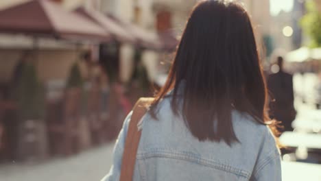 Vista-Trasera-De-La-Elegante-Joven-Caminando-Por-La-Calle-De-La-Ciudad-Como-Turista,-Luego-Girando-Hacia-La-Cámara-Y-Riendo-Alegremente