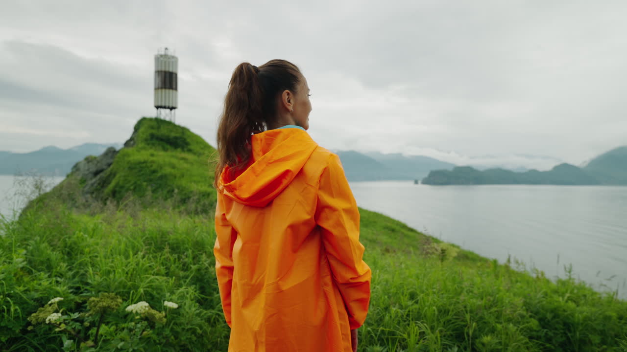 Woman in Orange Rain Jacket on a Coastal Hike