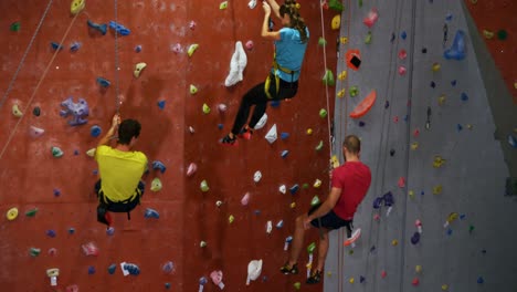 hombres y mujeres bajando por la pared artificial en el gimnasio de bouldering 4k