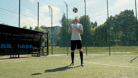 a young soccer man training freestyle tricks with the ball on a street football pitch on a sunny day 9