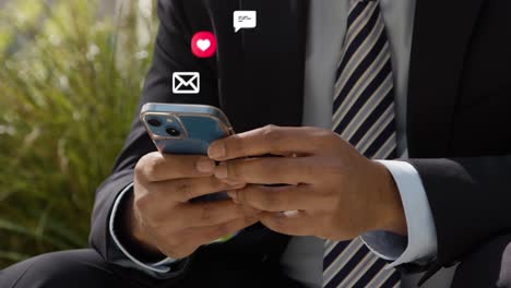 close up of businessman sitting outside city offices looking at mobile phone with motion graphics emojis showing multiple messaging and social media notifications 1