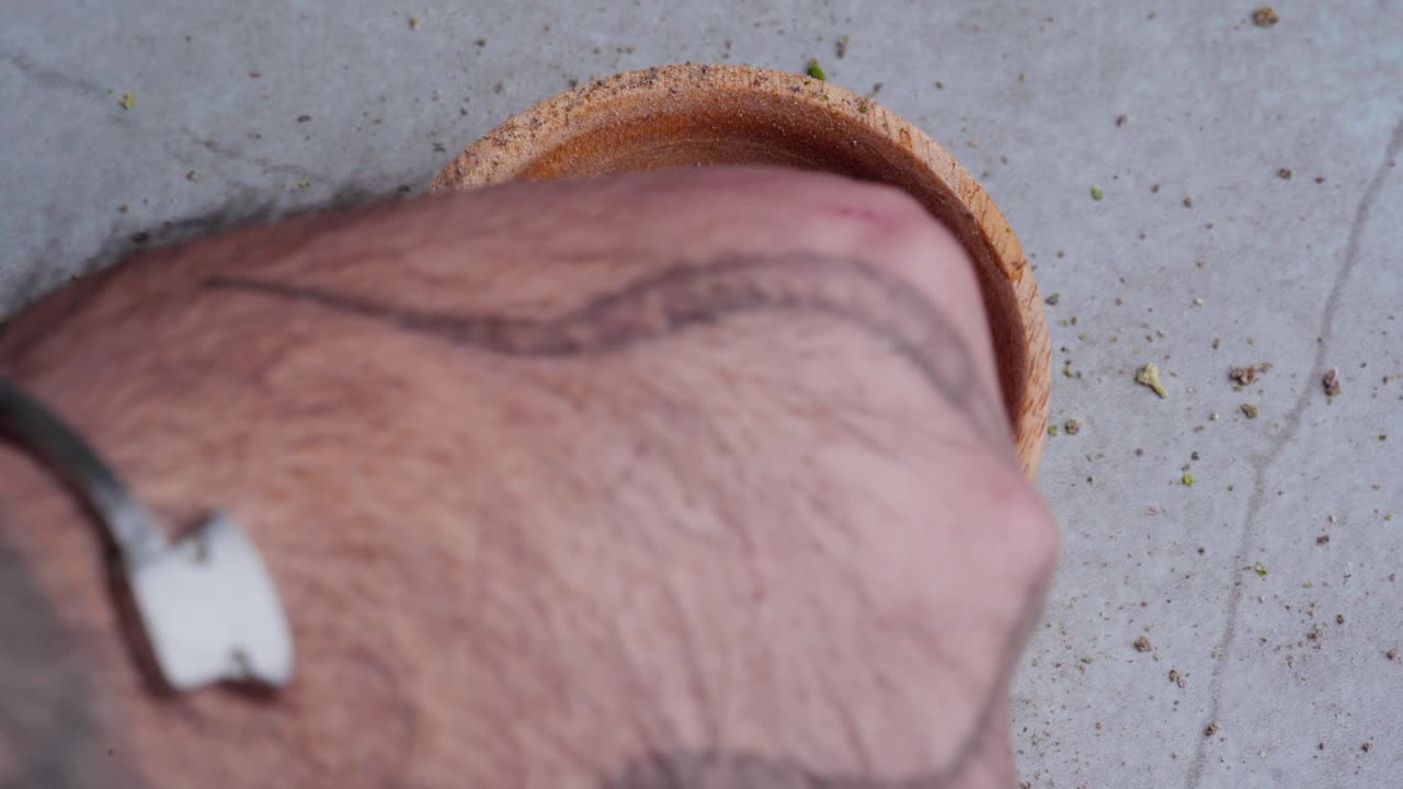 el hombre con tatuajes en la mano toma una pizca de marihuana del tazón para hacer cogollos de cannabis
