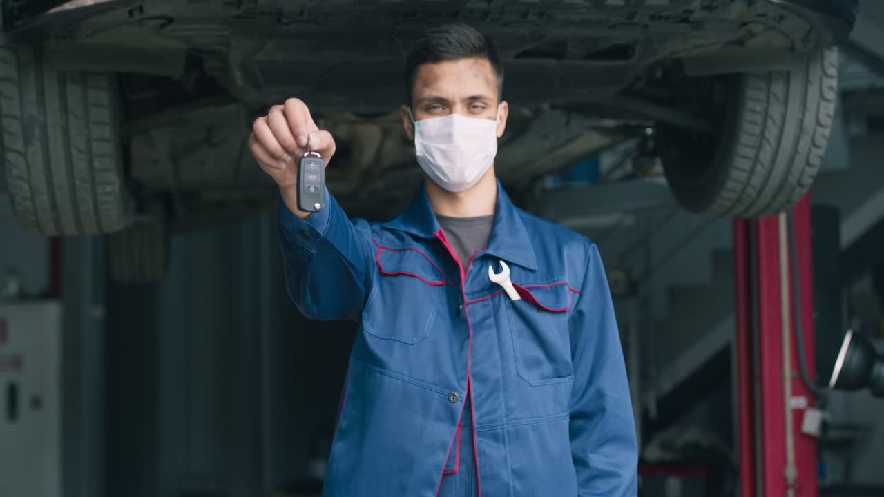 mecánico sosteniendo las llaves del coche en un garaje