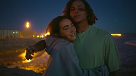 pareja abrazándose en la playa por la noche