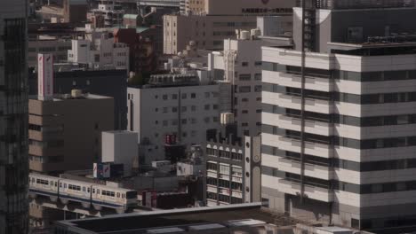 wide of japanese cityscape, kokura, kitakyushu, japan with monorail train in built-up architecture