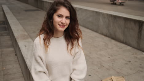 smiling girl looking at camera while holds cellphone