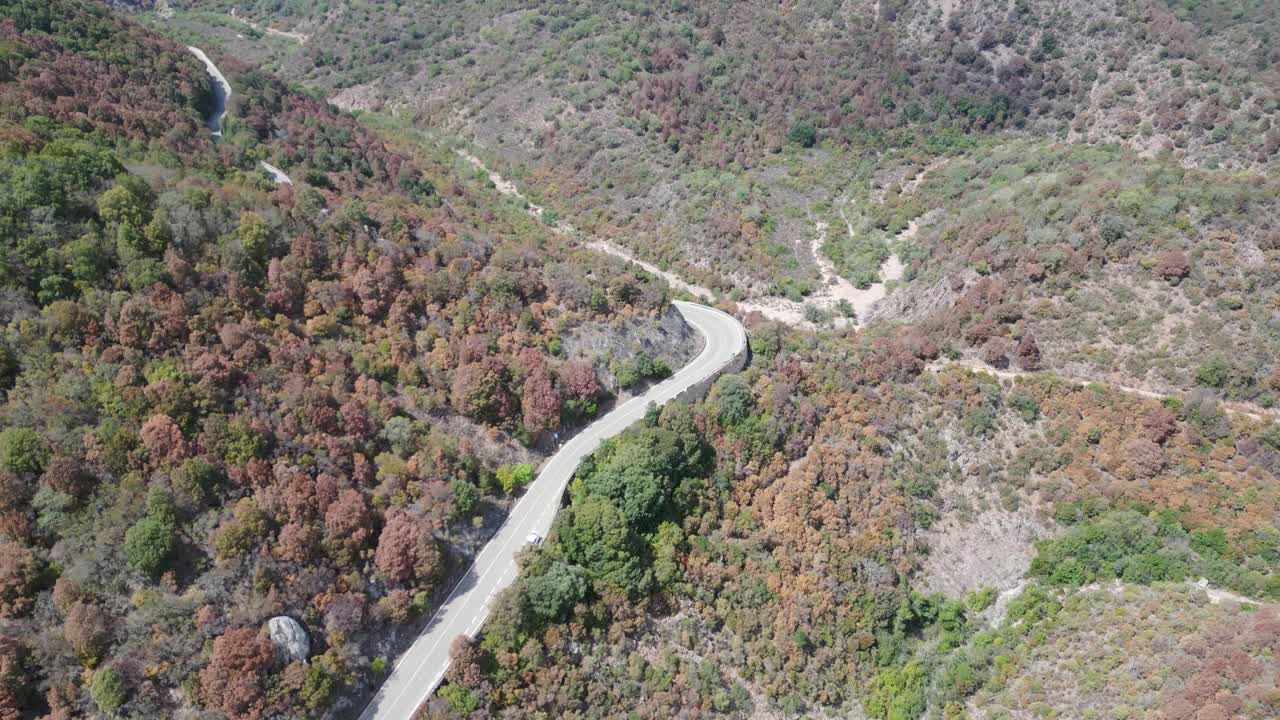 Aerial view of a road in the hills of Sardinia revealing a dry river bed