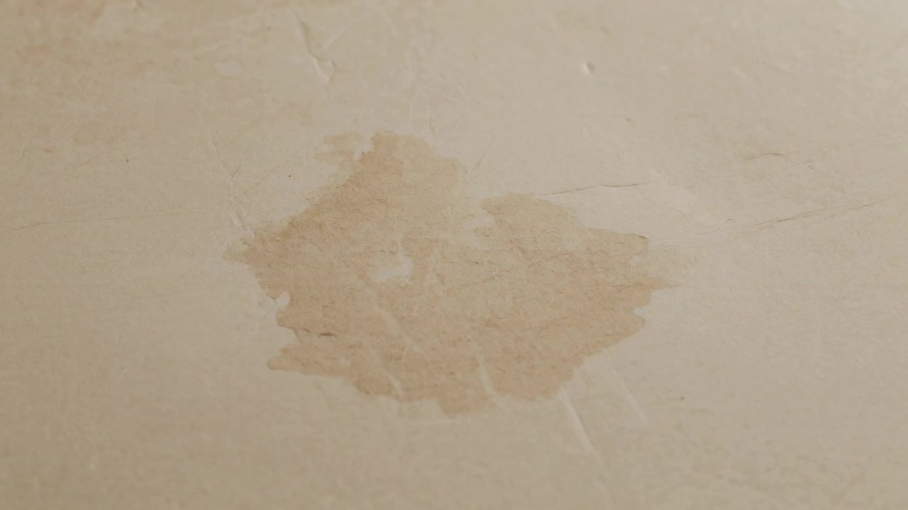 Capturing centered peeling paint patch staying still on beige wall, camera documenting water damage