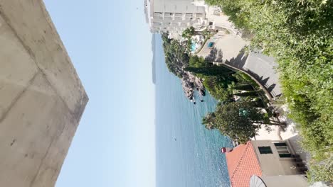 Reveal-shot-of-a-blonde-girl-taking-photos-on-the-beautiful-coast-of-Dubrovnik,-Croatia