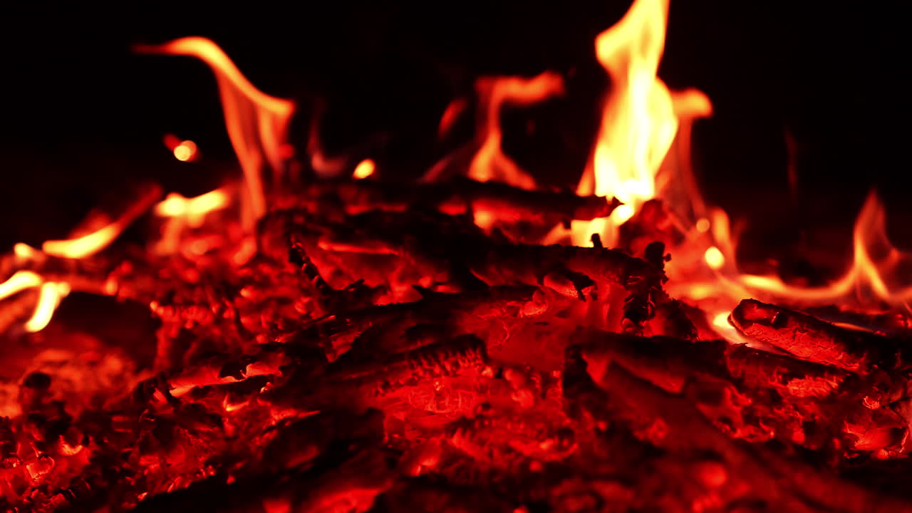 Amazing red hot embers left from the campfire. Little flames are burning at backdrop.