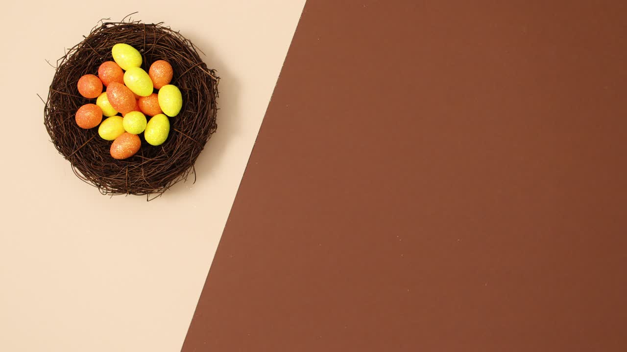 los huevos de pascua naranja y amarillos aparecen en el nido sobre un fondo marrón desnudo.