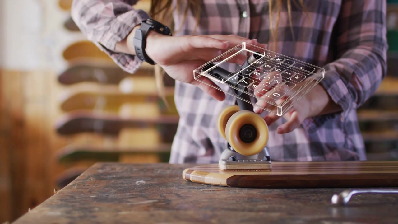 Donna che assembla truck e ruote su una tavola da skateboard, serrando i bulloni e facendo girare la ruota, guidata da un wireframe di un negozio di skate.