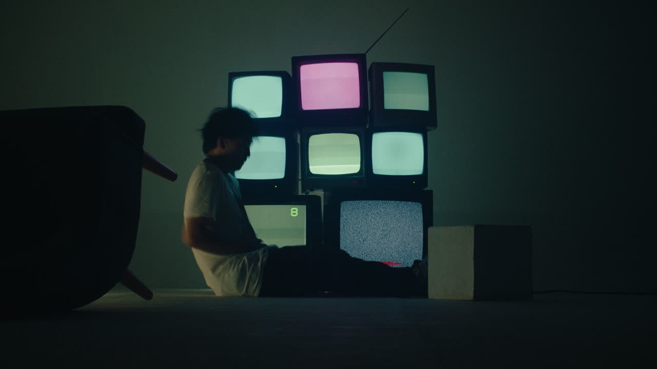 Young alternative boy Sitting Alone in the Dark room with Vintage crt TVs , isolation craziness sleep deprivation depression anxiety mental health problem