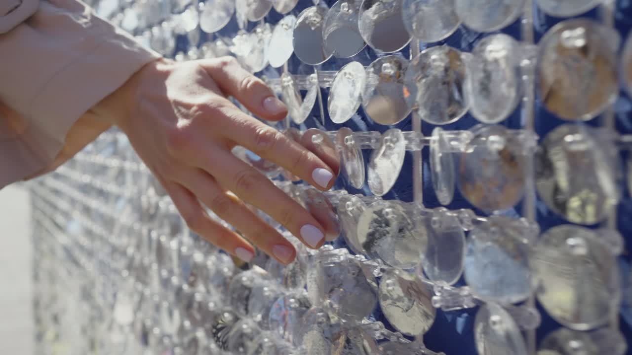 Female hand touches city wall decorated with shiny sequins