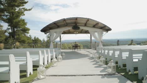 walking down the isle of a beautiful outdoor wedding ceremony venue with the gatineau hills and a sunny cloud filled blue sky in the background at le belvédère in wakefield, quebec, canada