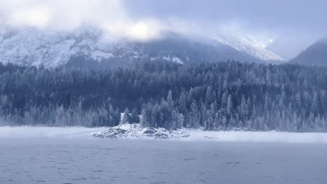 Panning-shot-of-the-landscape-view-of-the-snowy-mountains-from-the-river-in-Revelstoke,-British-Columbia