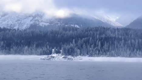panning shot of the landscape view of the snowy mountains from the river in revelstoke, british columbia