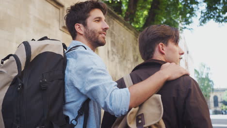 rear view of loving male gay couple hugging walking along city street together