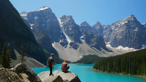 couple sitting on a rock near riverside 4k