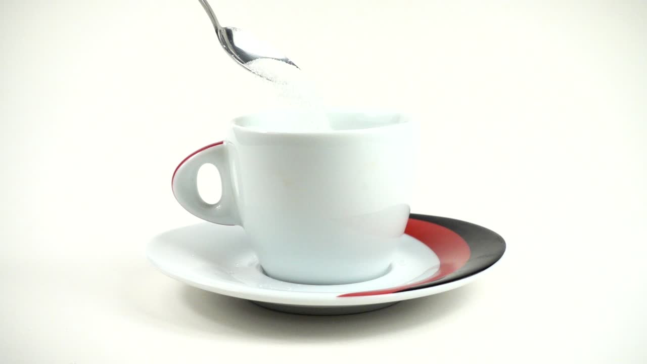 Dalla cucchiaio lo zucchero viene versato in una tazza. Movimento lento