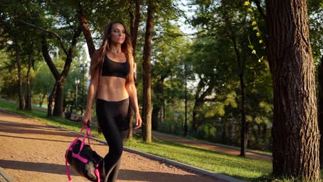 Hermosa-Mujer-Morena-Caminando-Con-Bolsa-De-Deporte-En-El-Parque.-Mujer-Deportiva-Sana-Y-En-Forma-Haciendo-Ejercicio-Por-La-Mañana.-Tiro-En-Cámara-Lenta