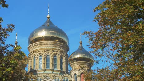 view of orthodox st nicholas naval cathedral golden domes and crosses on blue sky in sunny autumn day at karosta, liepaja, wide shot