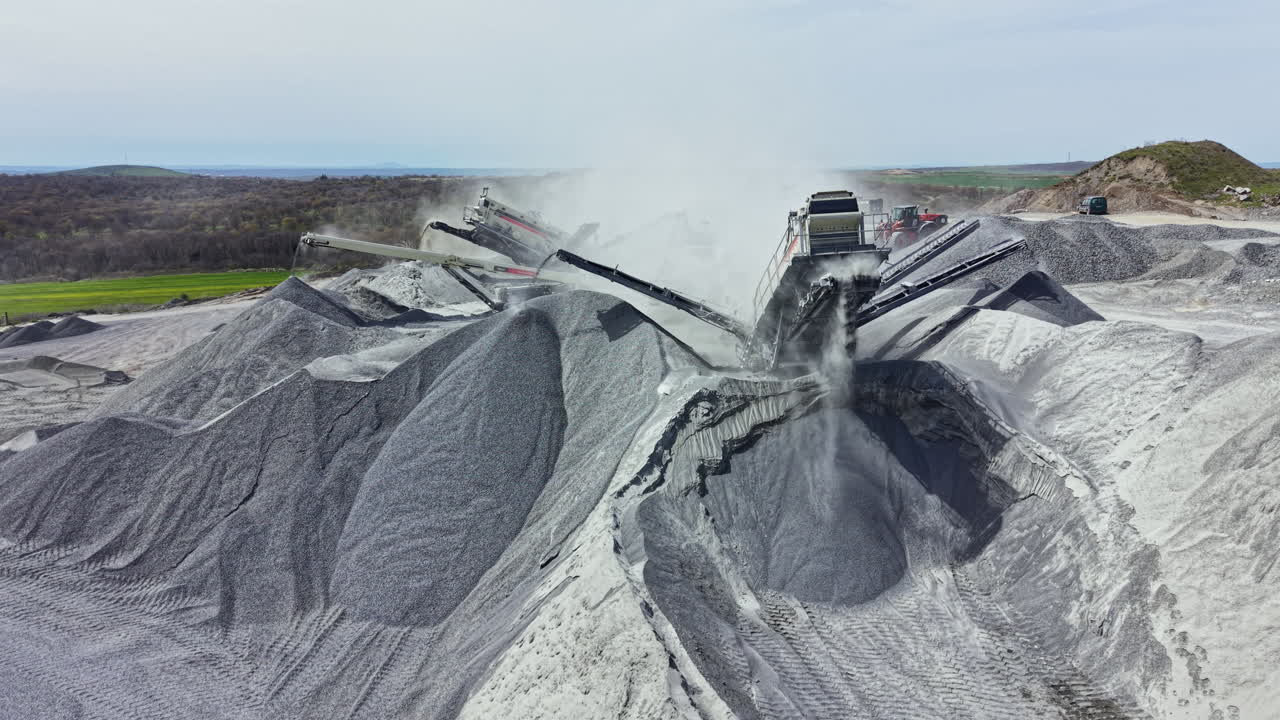 Granite quarry operation shows large machinery crushing rock and moving materials in the mining area