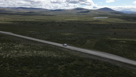 El-Dron-Captura-La-Furgoneta-Que-Conduce-A-Través-De-La-Interminable-Carretera-Aislada-Y-El-Parque-Nacional-De-Rondane-En-El-Fondo-Se-Puede-Ver-En-El-Fondo