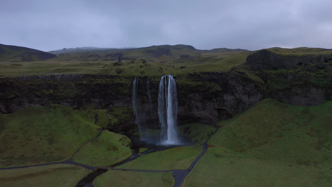 Aerial: Flying towards the Seljalandsfoss waterfall in Iceland on a cloudy day