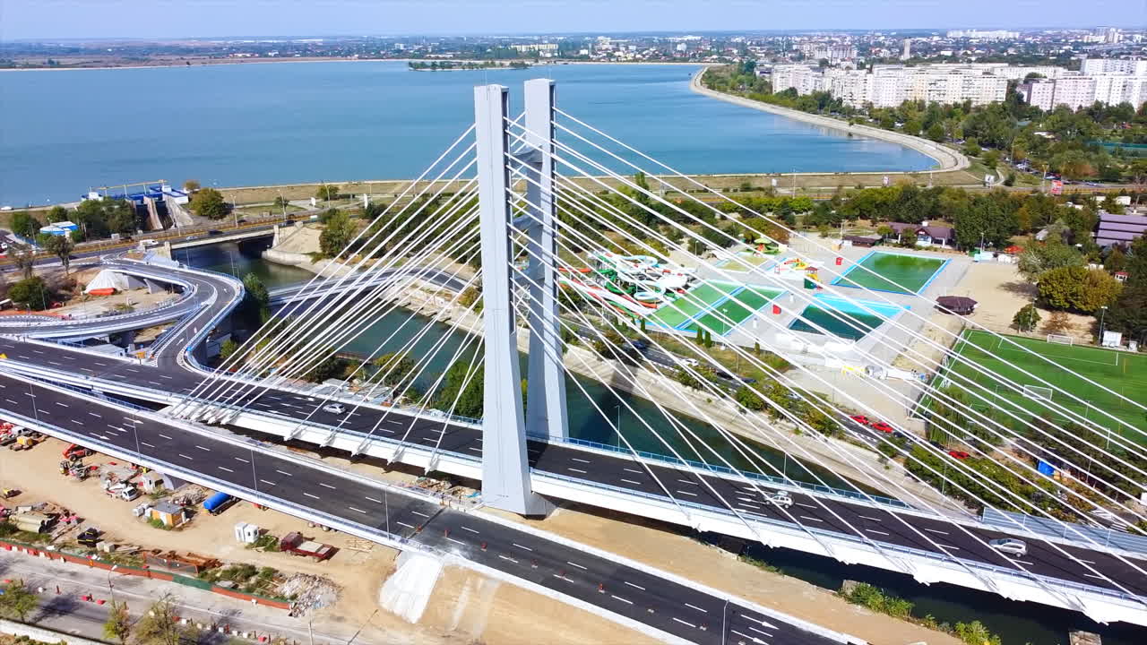 Ciurel passage, bridge over a river with moving cars, construction works, field and TV tower near it. Residential buildings on the background. View from the drone. Bucharest, Romania