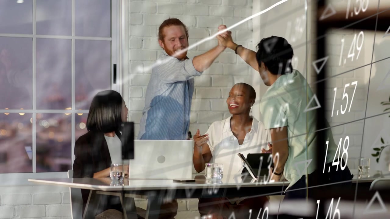 Team celebrating results after finance charts appearing on glass, pointing at laptop tablet