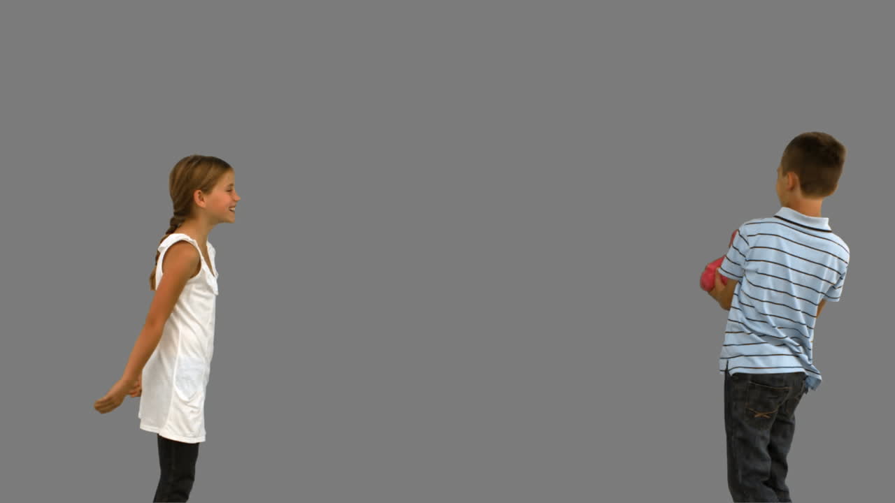 hermanos jugando con un cojín en forma de corazón en la pantalla gris