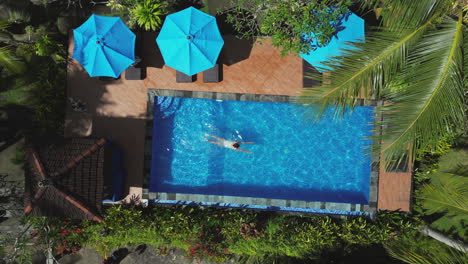 asian girl swims in relaxing pool at tropical holiday resort in indonesia