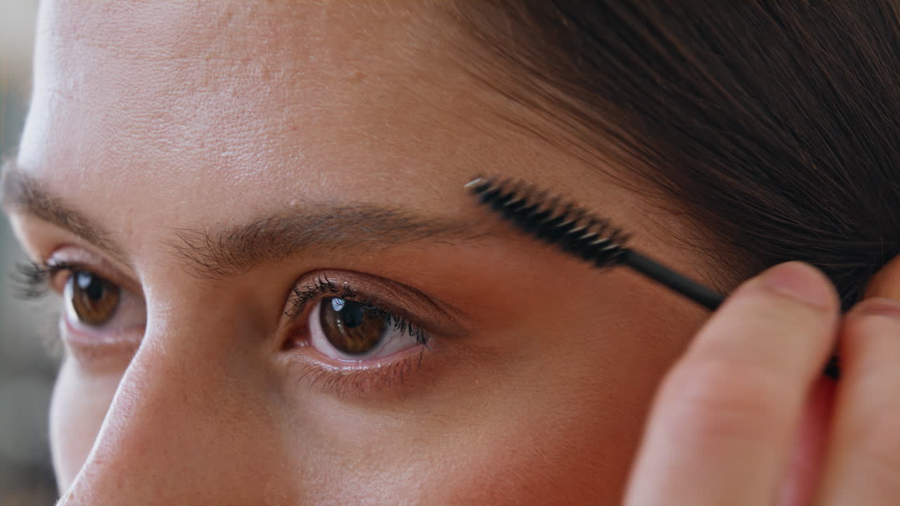 Pretty woman grooming eyebrows with brush at home closeup. Lady styling brows