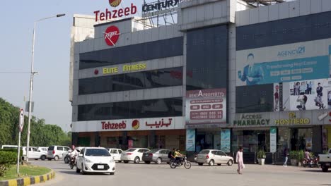 a shot capturing an impressive commercial structure situated along the main road, surrounded by cars under a clear blue sky.
