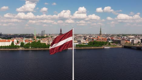 drone orbits around latvian flag blowing in wind