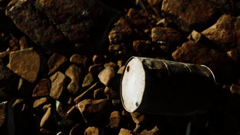 barril de metal oxidado destruido en las rocas de la playa