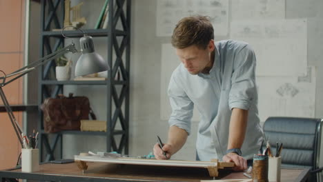 Architect-man-sits-at-drafting-table-in-modern-industrial-office-during-the-day.-Architect-working-on-blueprint-with-spesial-tools-and-pencil-close-up.-Male-architect-at-work-only-hands-with-ruler-and-pencil.-Design-of-the-house.-Engineer.-Tools-for-drawing.-Creating-a-drawing.