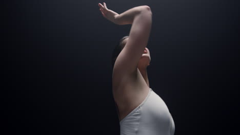 tender dancer looking upward indoors. beautiful ballerina dancing in dark class.