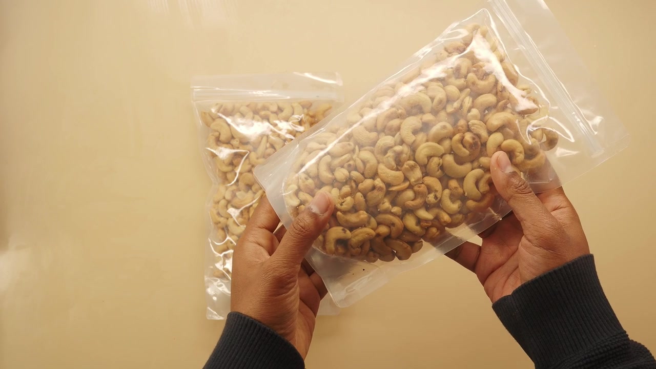 Person Holding Two Transparent Bags of Cashew Nuts