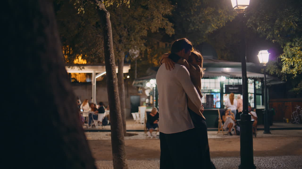 Coppia adorabile che si abbraccia a un appuntamento su una strada illuminata di notte. Famiglia felice che si gode il momento.