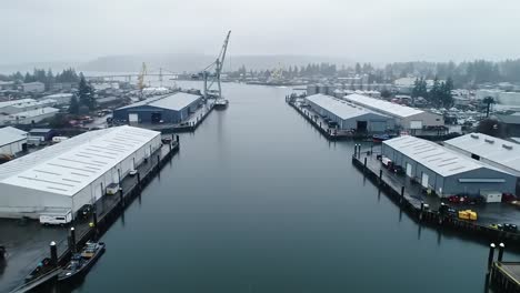 setting showcases an active port with tranquil waters surrounded by industrial buildings. cranes and boats indicate a lively maritime environment in the fog.