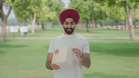 hombre indio sikh feliz recibe un regalo en el parque