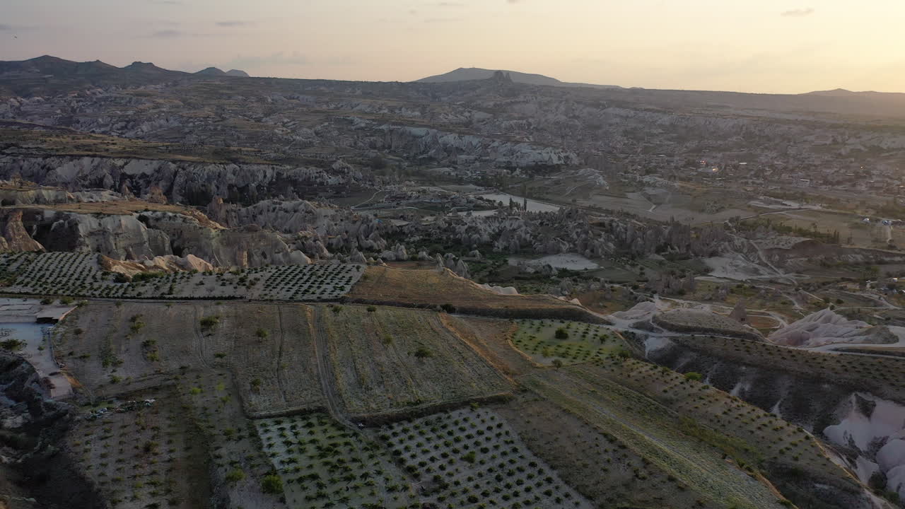 Spettacolare ripresa aerea cinematografica con drone che sorvola i campi agricoli sulle montagne rocciose che circondano la Cappadocia, Turchia
