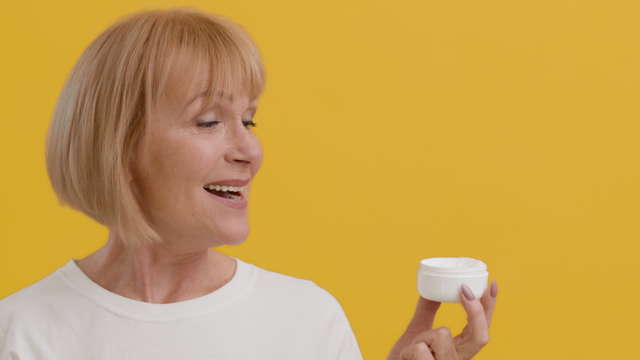 미용 크림 항아리를 들고 있는 미소 짓는 고위 여성