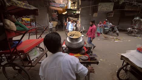 man pushing cart onto busy indian road