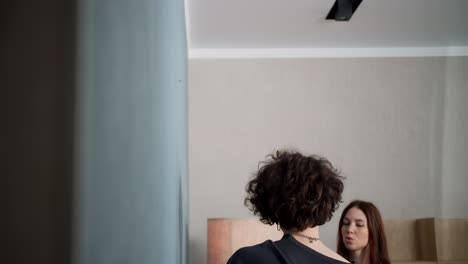 a brunette guy with curly hair arrives with a nail in the wall and hangs a clock together with a girl who helps him at home