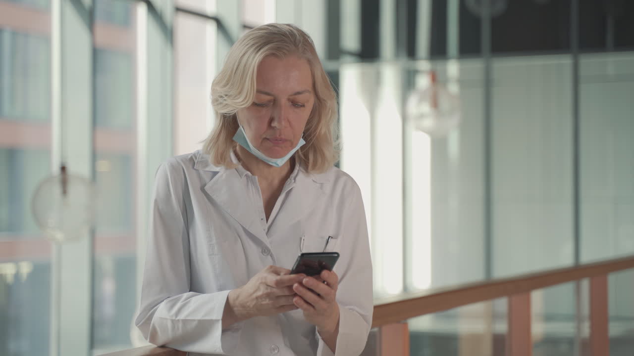 una doctora rubia de mediana edad envía un mensaje de texto a un teléfono móvil