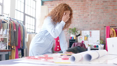 Portrait-of-happy-biracial-female-fashion-designer-standing-at-table-working-in-studio,-slow-motion